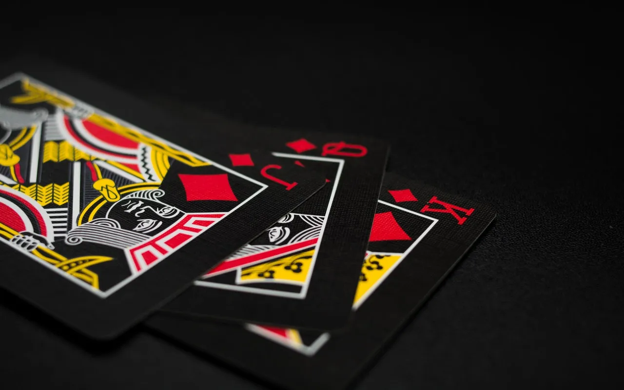 A stack of three black poker cards displaying jack, queen and king
