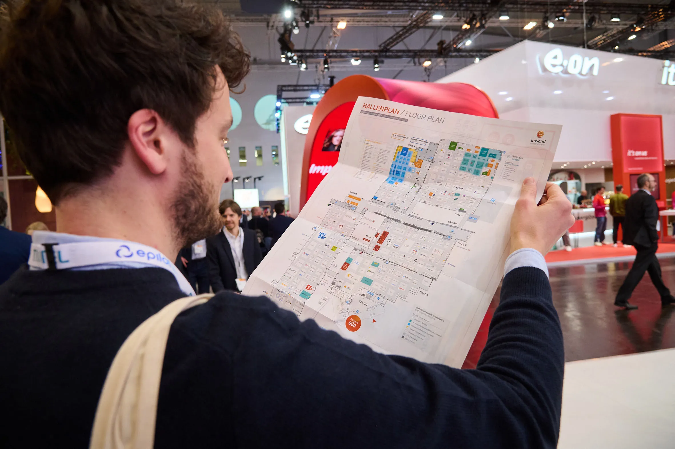 Mann mit Hallenplan in den Händen vor dem eon Messestand